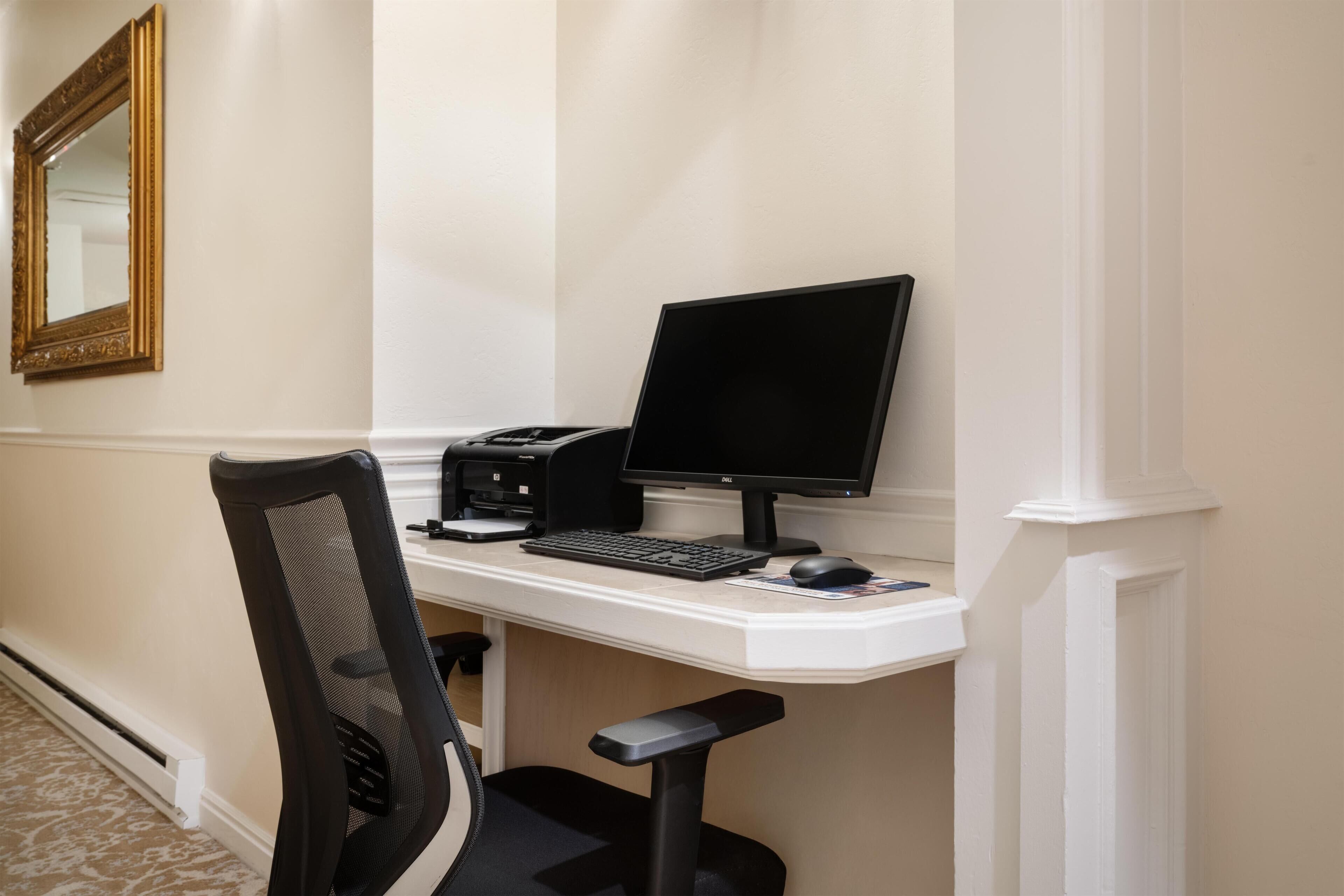 Un bureau avec un ordinateur, un clavier et une souris, une chaise et un miroir accroché au mur.