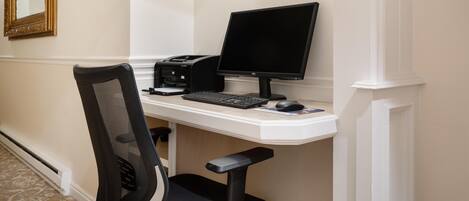 Un bureau avec un ordinateur, un clavier et une souris, une chaise et un miroir accroché au mur.