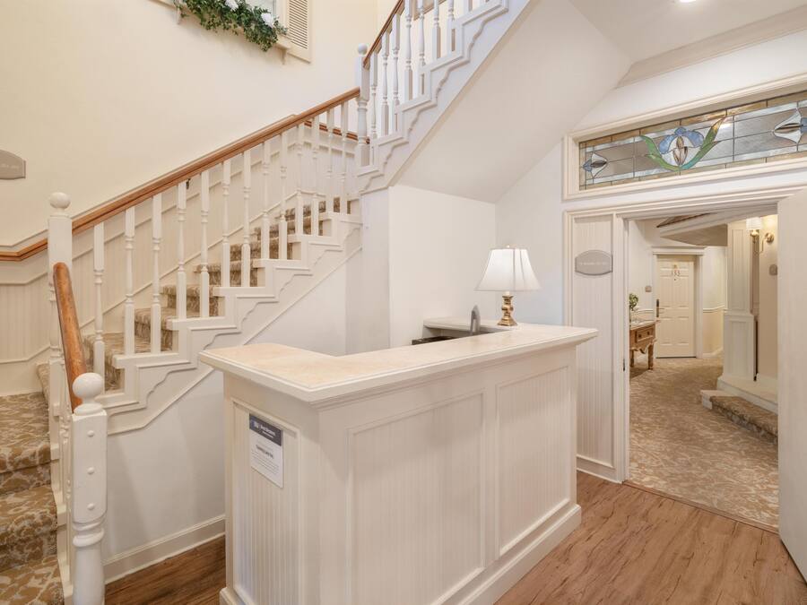 A reception area with a staircase, a reception desk, and a door leading to a hallway.