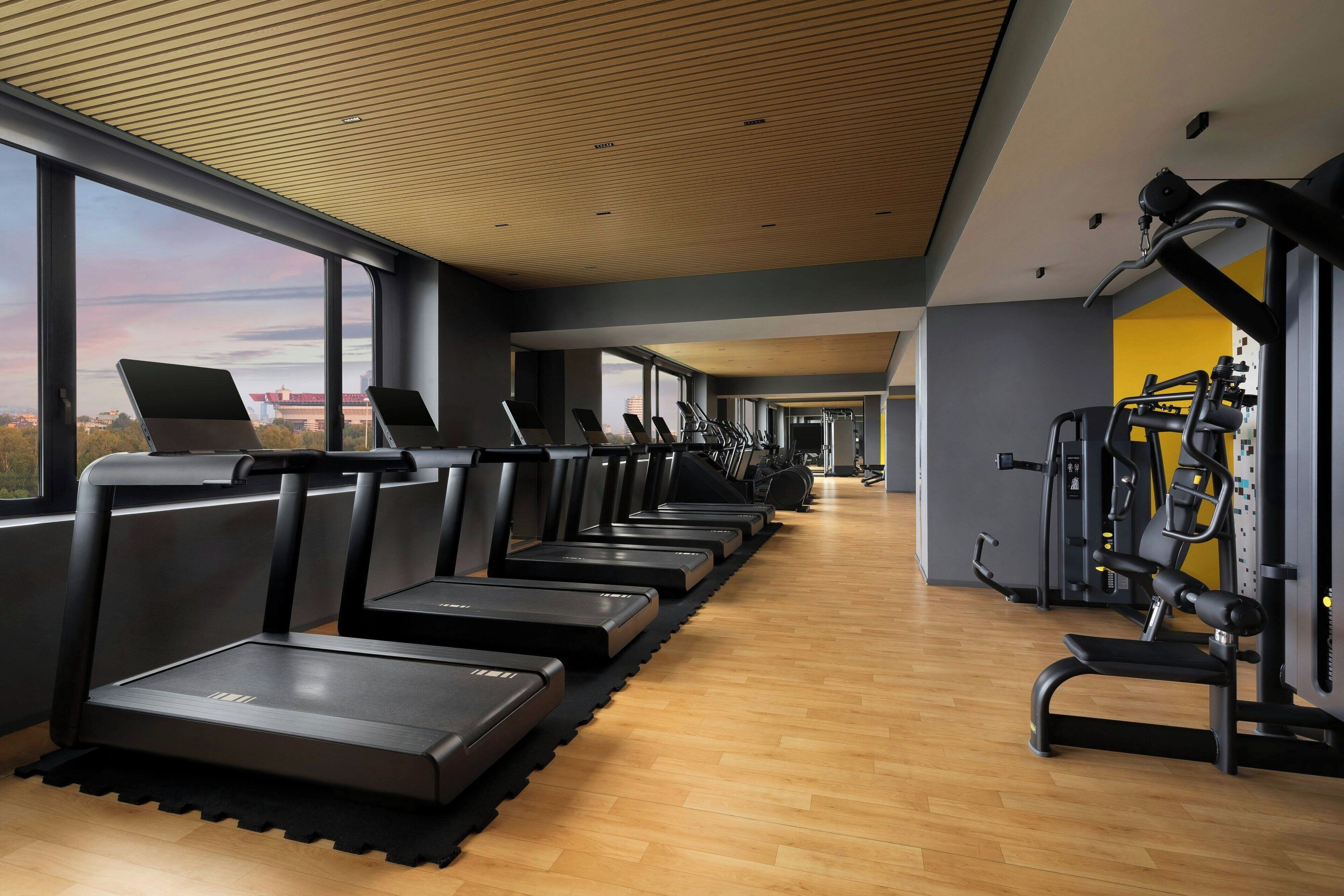 Une salle de sport équipée de tapis de course, de vélos d’exercice et d’appareils de musculation.