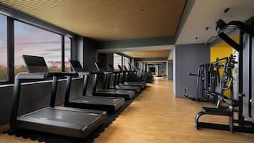 Un gimnasio con cintas de correr, bicicletas estáticas y máquinas de pesas.