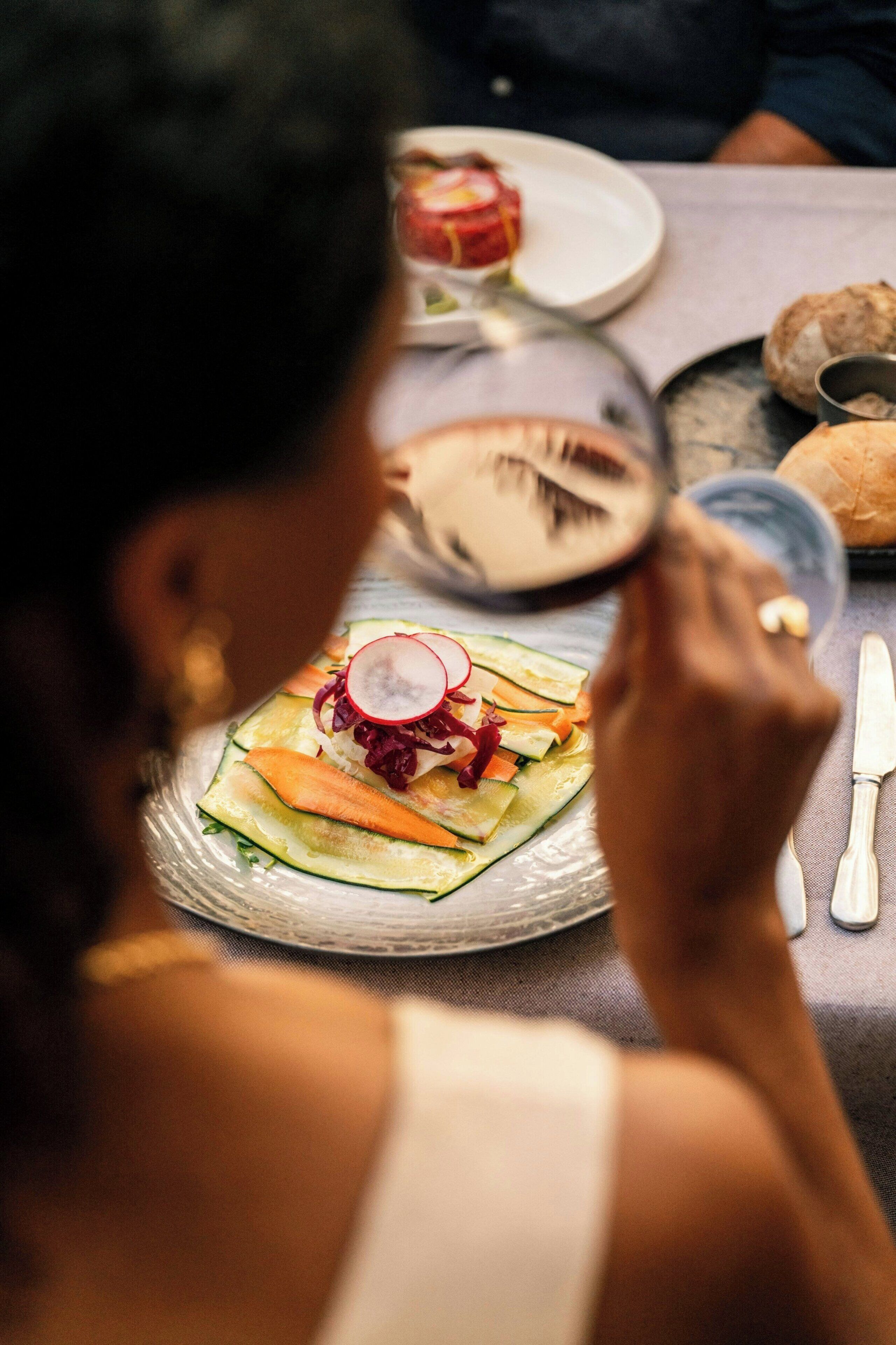 Una mesa con platos de comida, una copa y cubiertos.