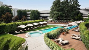 A rooftop pool area with lounge chairs, a swimming pool, and a view of surrounding buildings. - Sheraton Milan San Siro (Milan)