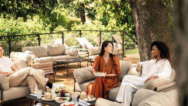 A group of people seated on outdoor furniture, with a dining table in front of them. - Sheraton Milan San Siro (Milan)