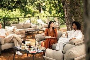A group of people seated on outdoor furniture, with a dining table in front of them. - Sheraton Milan San Siro (Milan)
