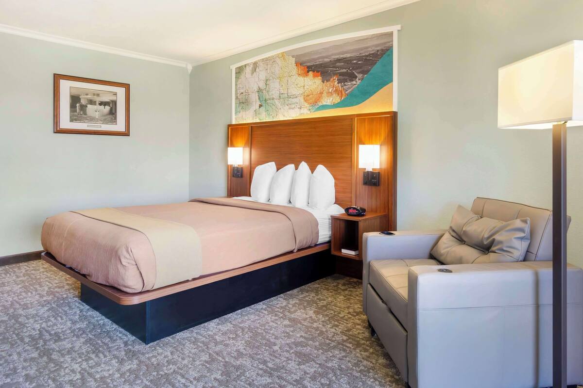 Une chambre d’hôtel avec un lit, un canapé, une table de chevet et une carte accrochée au mur.