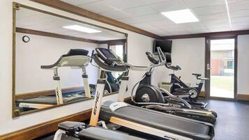 Un gimnasio con cintas de correr, una bicicleta estática y una banca.