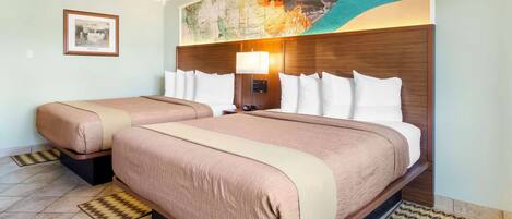 A hotel room with two beds, a large map mural, a framed picture on the wall, and a modern headboard.