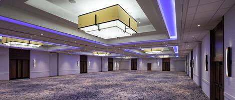 A spacious hotel lobby with a patterned carpet, recessed lighting, and a modern ceiling design.