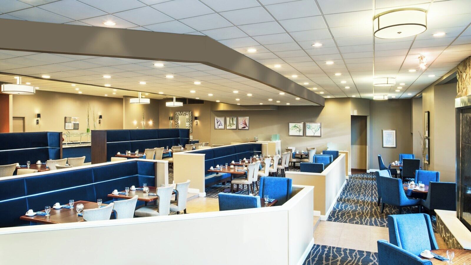 A hotel lobby with multiple seating areas, including booths and tables, and a patterned carpet.