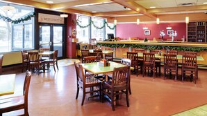 Un restaurante con mesas y sillas de madera, una zona de bar y decoraciones festivas.