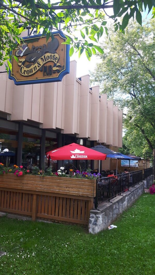 A building with a sign that reads 'Crown & Moose' and outdoor seating with red and blue umbrellas.