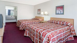 Ein Hotelzimmer mit zwei Betten, einem Schreibtisch, einem Spiegel und Bildern an den Wänden.