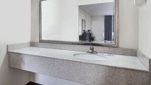 Ein Badezimmer mit Granitplatte, Waschbecken, Spiegel und Handtuchhalter.