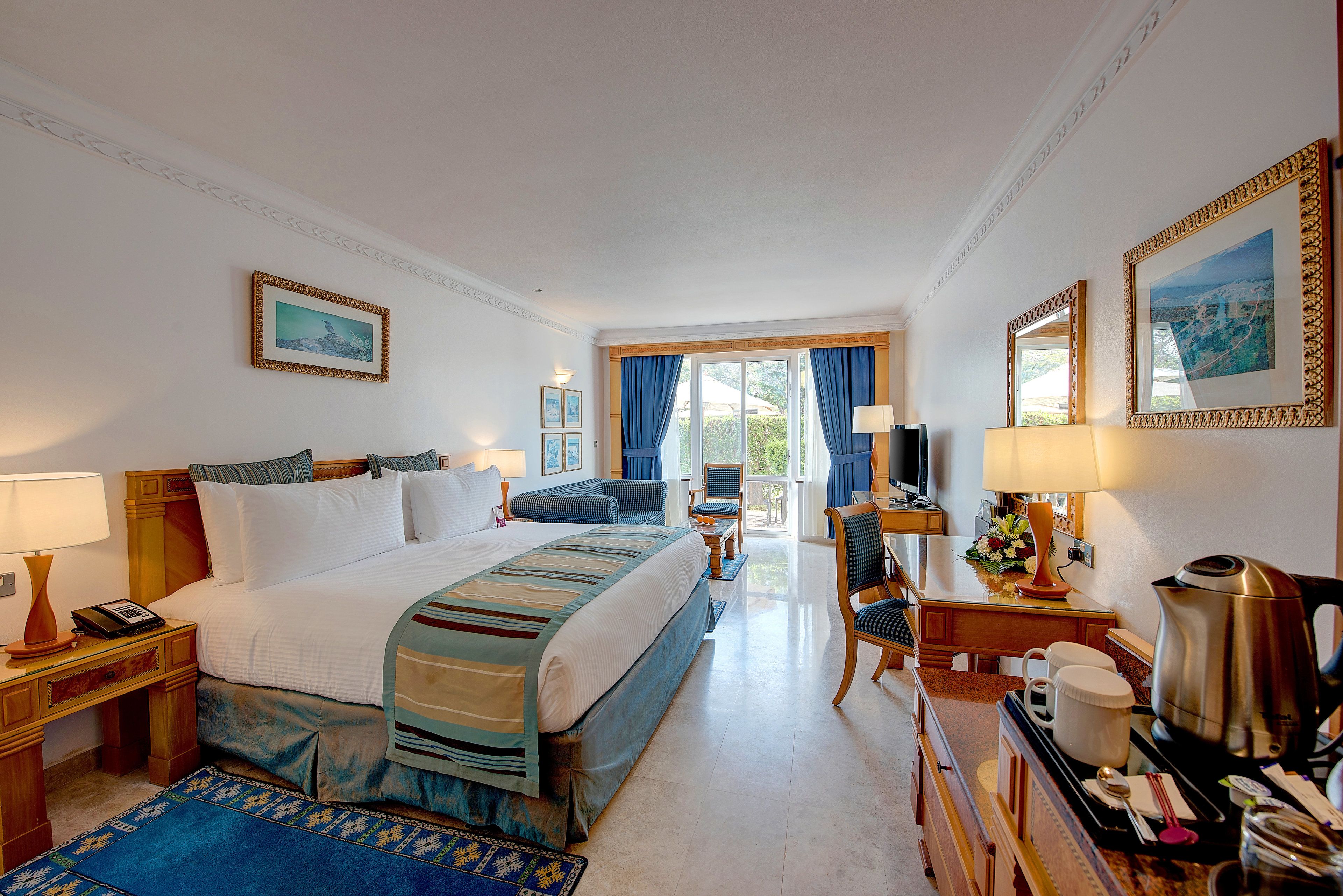Habitación de hotel con una cama grande, un escritorio con cafetera y vistas al exterior.