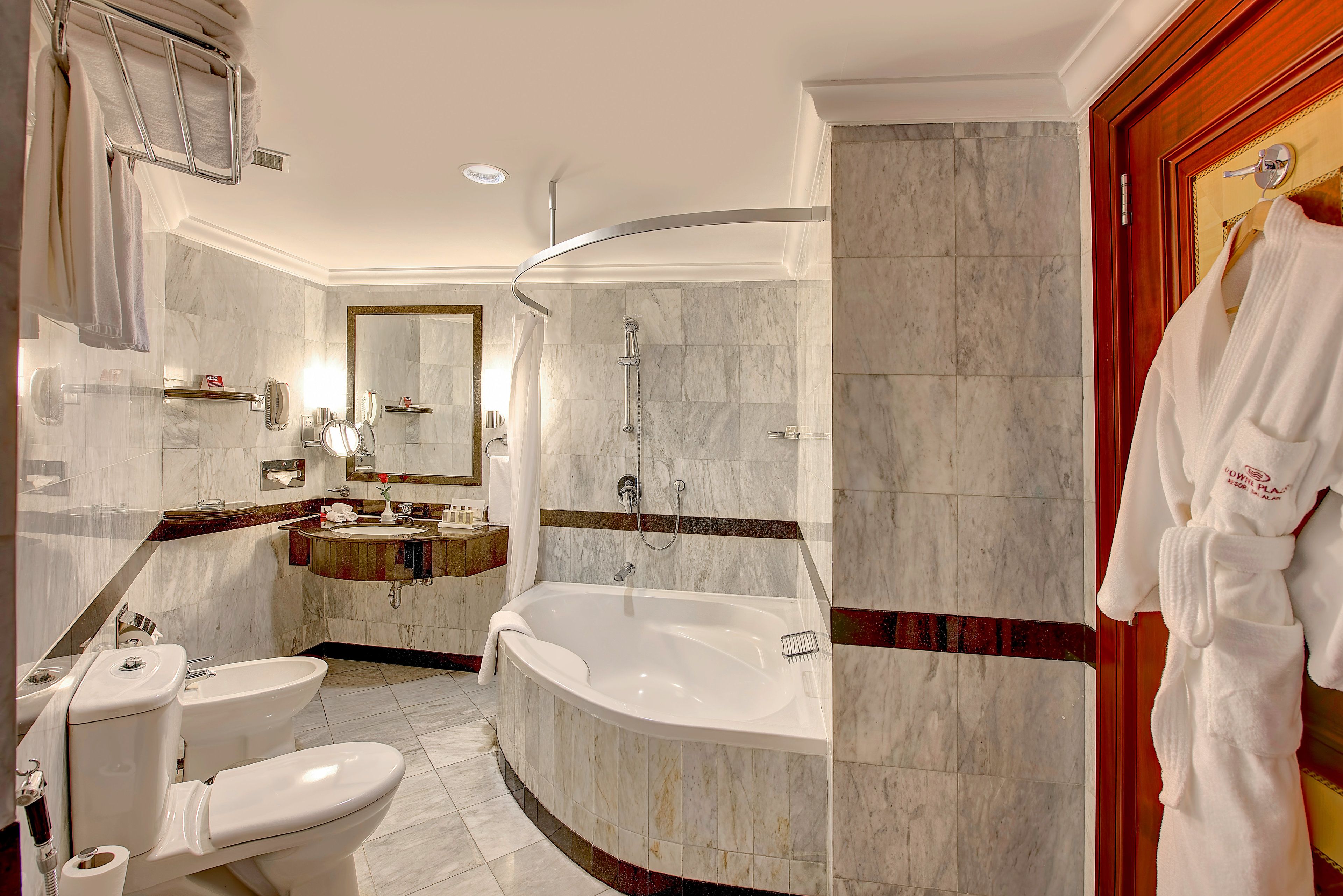 A modern bathroom with a freestanding bathtub, a vanity with a mirror, a toilet, and a towel rack.