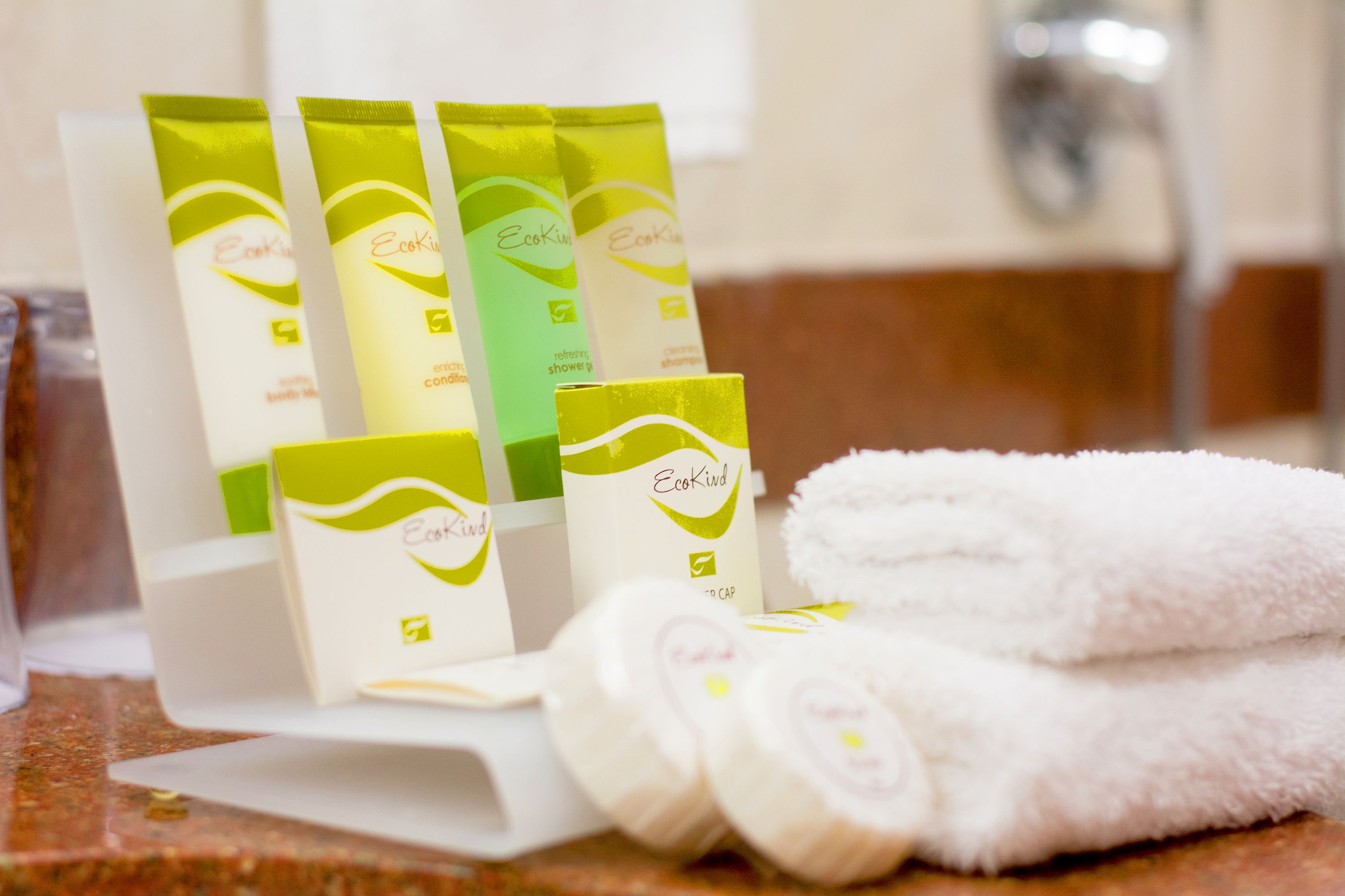 A bathroom with a sink, a mirror, and toiletries including EcoKind shower gel and shampoo.