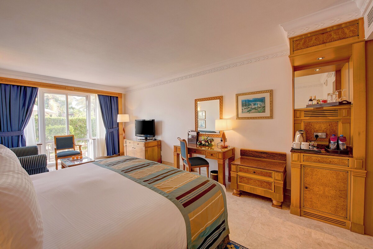 Habitación de hotel con una cama grande, un escritorio con ordenador, televisión y armario.