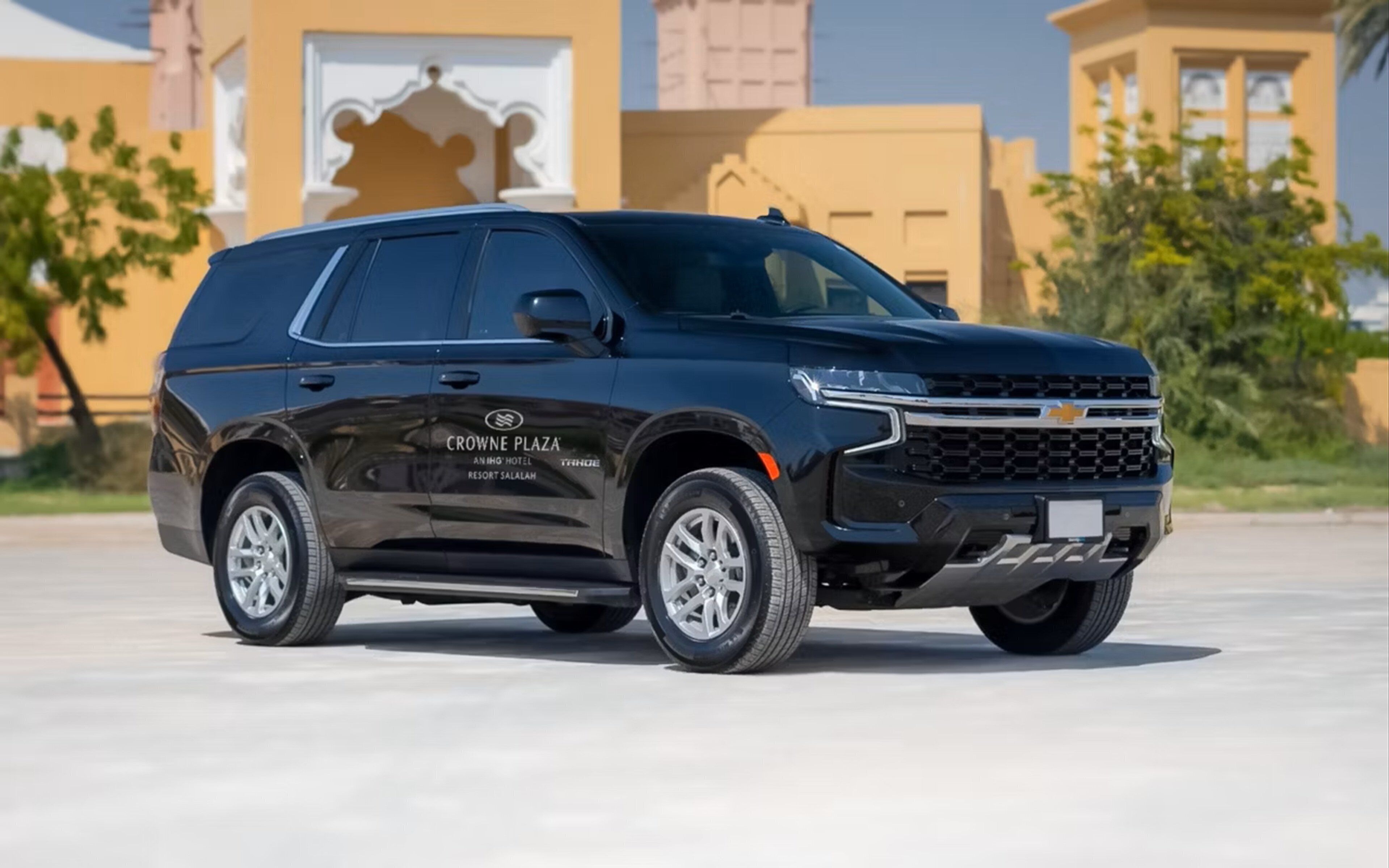 A black Chevrolet SUV parked in front of a building with the text "CROWNE PLAZA ANING HOTEL RESORT SALALAH" on its side.