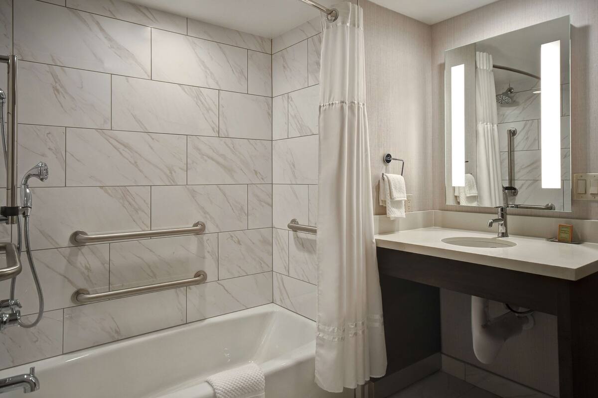 A modern bathroom with a bathtub, a shower, and a vanity with a sink and mirror.