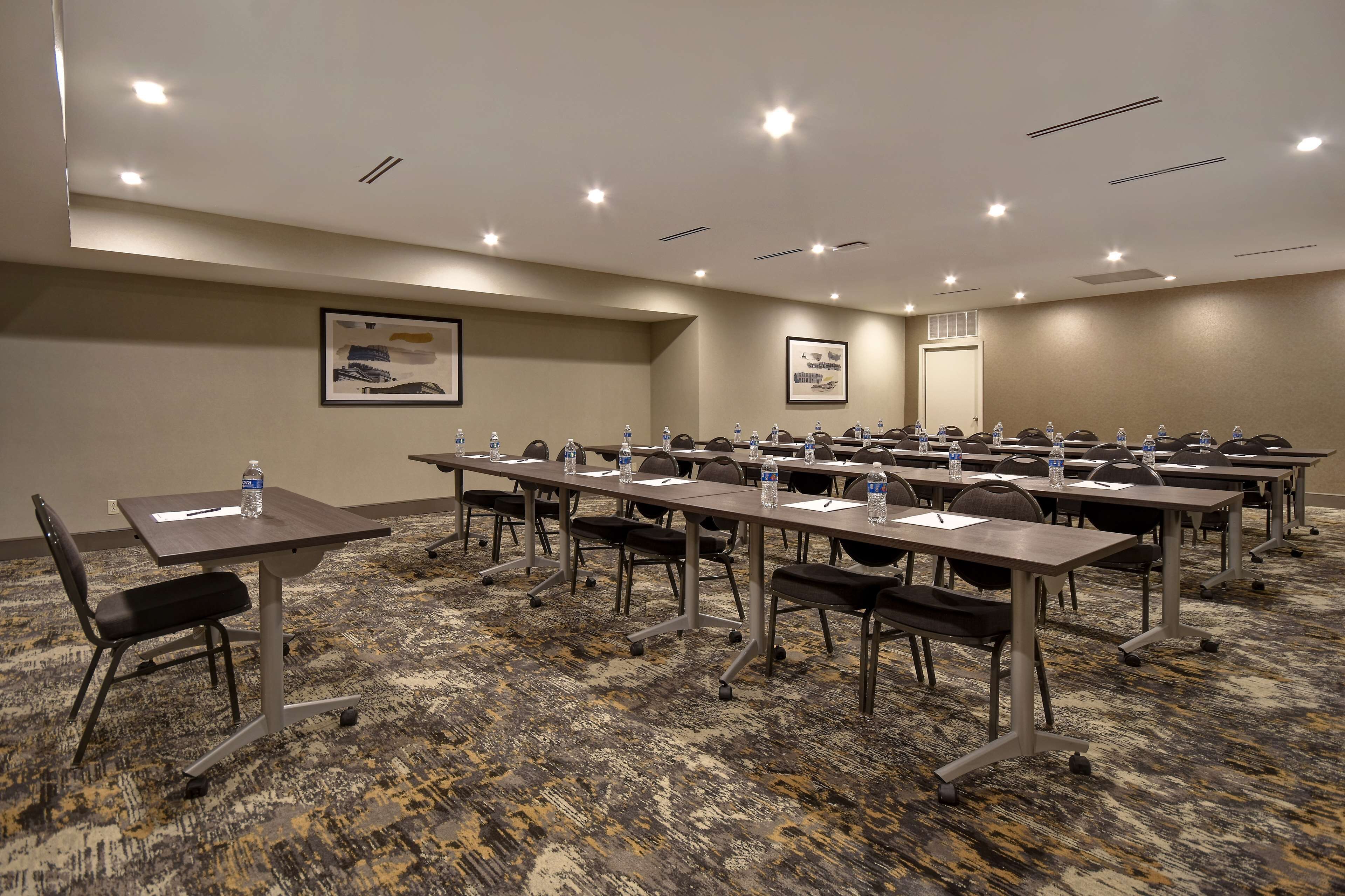A conference room with multiple tables, chairs, and water bottles.