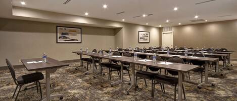 A conference room with multiple tables, chairs, and water bottles.
