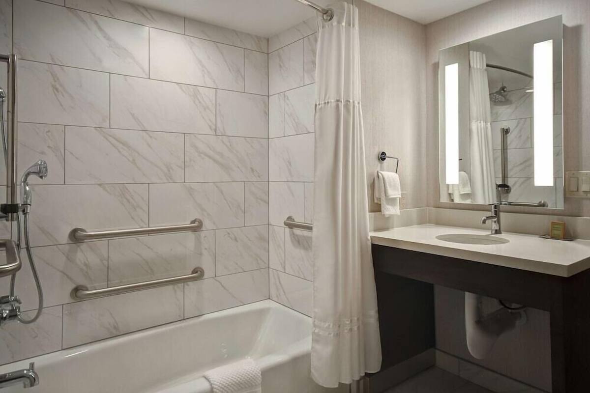 A modern bathroom with a bathtub, shower, and vanity with a mirror.