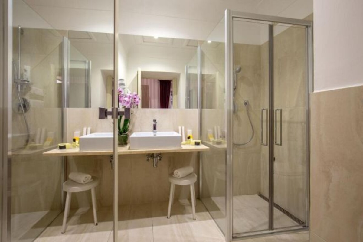 Een moderne badkamer met een douchecabine van glas, twee wasbakken en een spiegel.