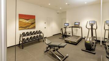 A gym with exercise equipment, a treadmill, and a bench press.