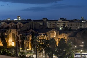 Un complesso di edifici storici con finestre ad arco e una cupola centrale, illuminato di notte.