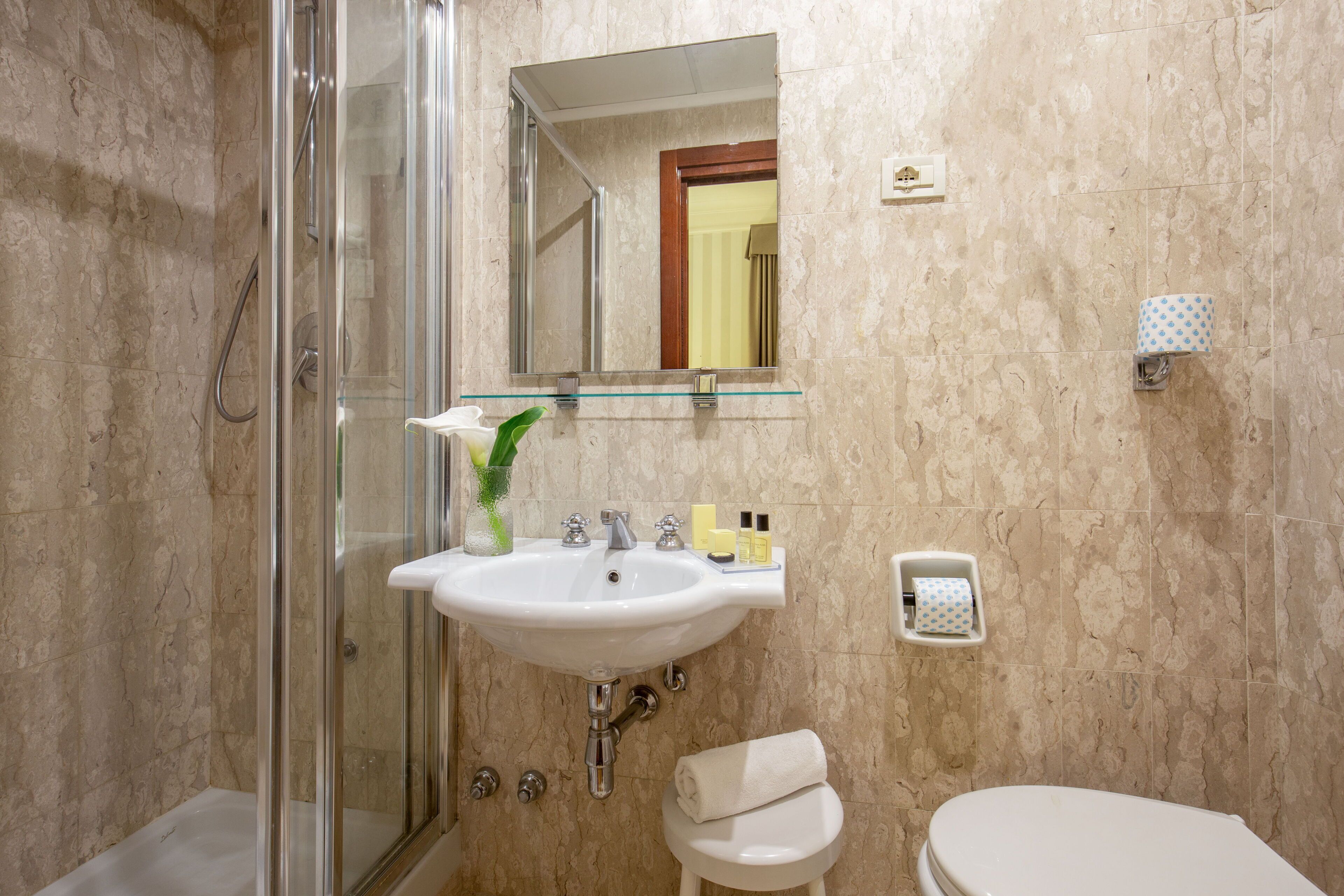 Un baño con cabina de ducha de vidrio, un lavabo con espejo y un inodoro.