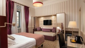 A hotel room with a bed, a sofa bed, a desk with a lamp, a television, and a coffee maker. - Hotel Nord Nuova Roma (Rome)