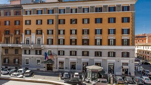 A multi-story hotel with a central entrance, balconies, and a parking area with cars. - Hotel Nord Nuova Roma (Rome)