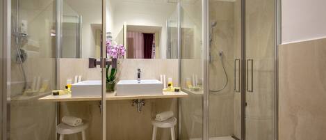 A modern bathroom with a glass-enclosed shower, two sinks, and a vanity with a mirror.