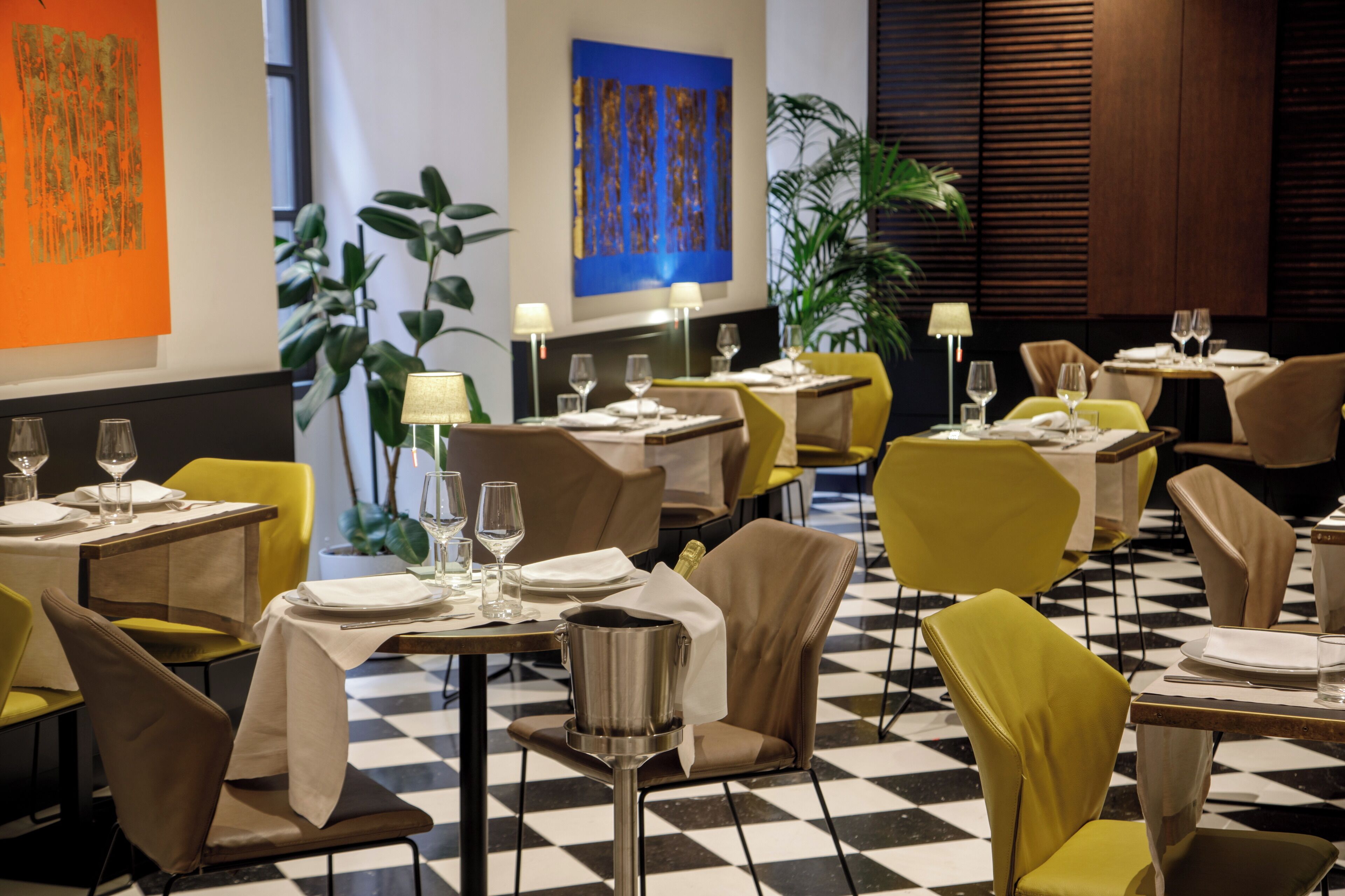 Un restaurant avec des tables dressées, des chaises et un sol à carreaux.