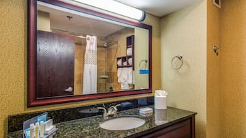 A bathroom with a large mirror, a sink, and a towel rack.