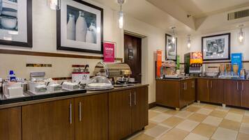 A hotel breakfast area with a counter displaying various food items and a coffee machine.