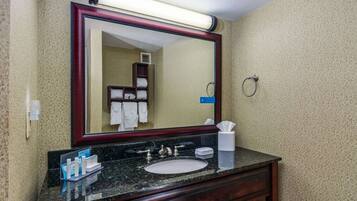 A bathroom with a large mirror, a sink, and a towel rack.