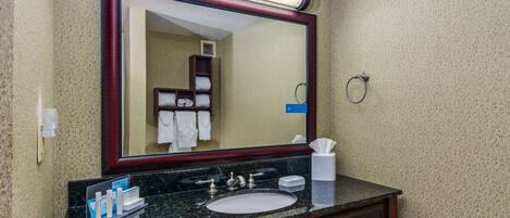 A bathroom with a large mirror, a sink, and a towel rack.