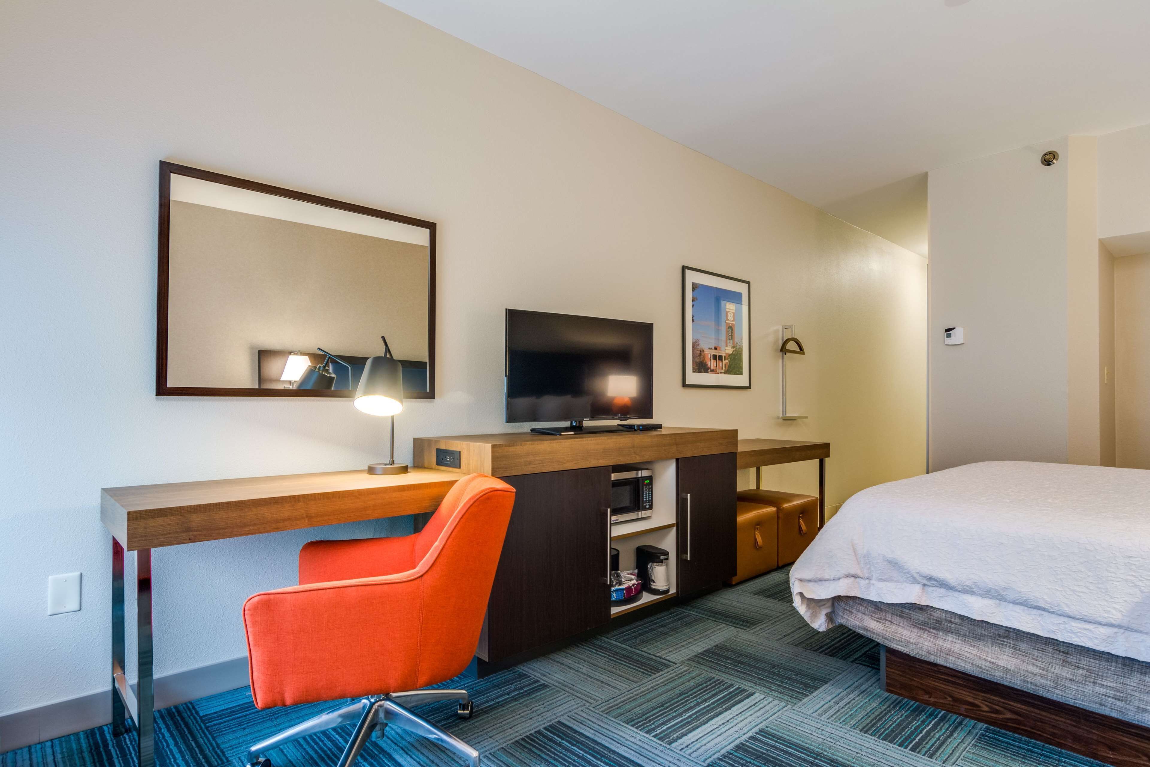 Ein Hotelzimmer mit Bett, Schreibtisch mit Stuhl, Fernseher, Mikrowelle und einer Kaffeemaschine.