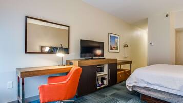 A hotel room with a bed, a desk with a chair, a television, a microwave, and a coffee maker.