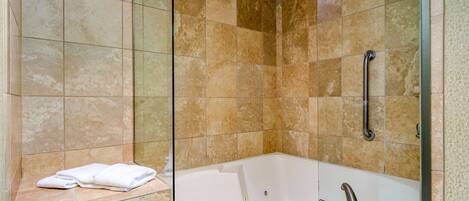 Une salle de bain moderne avec une douche à parois de verre, une baignoire blanche et des carreaux de couleur beige.
