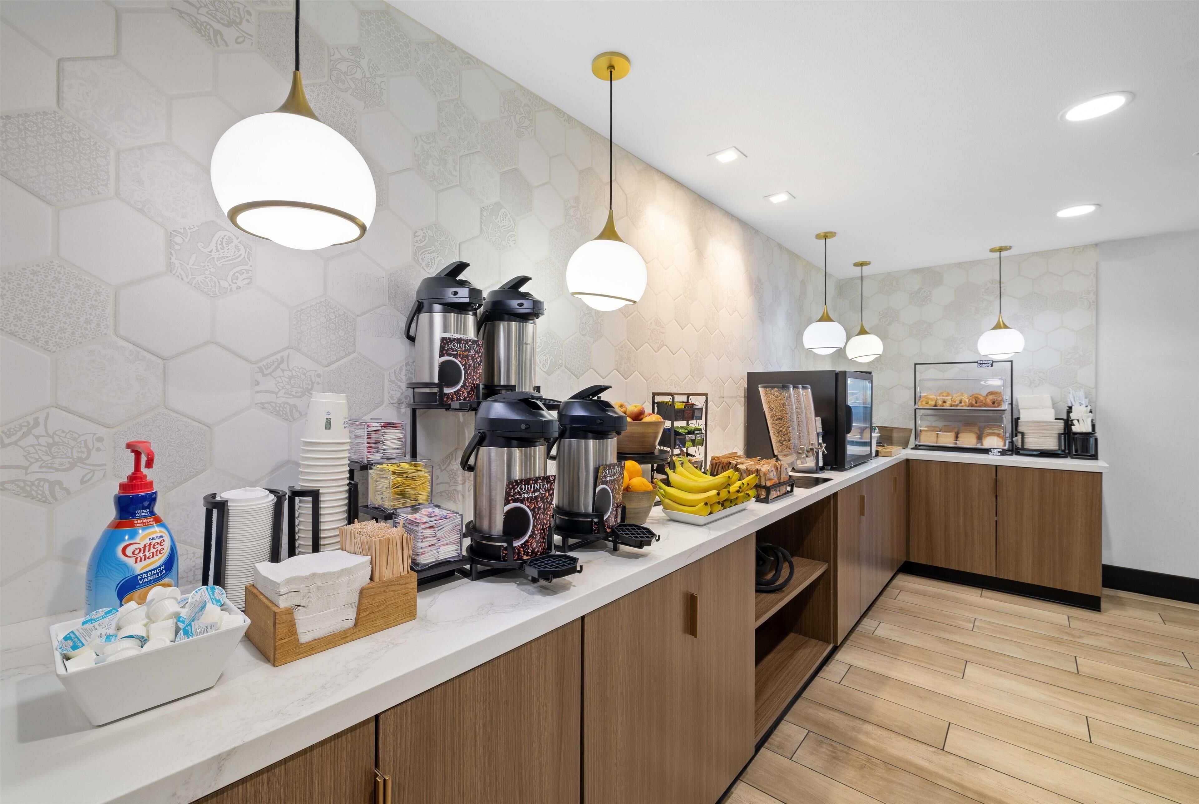 A modern kitchen area with coffee makers, a coffee machine, and a fruit display.