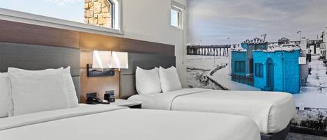 A hotel room with two beds, a stone wall, a mural of a pier, and a window.