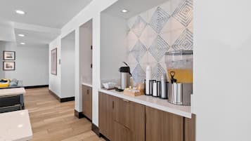 A modern kitchen with wooden cabinets, a marble countertop, and a geometric-patterned backsplash.