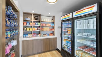 A snack and beverage kiosk with shelves stocked with various snacks and drinks, and a refrigerated section with bottled water and juices.