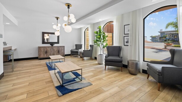 A modern lobby with a wooden floor, seating area, large windows, and a plant. - La Quinta Inn & Suites by Wyndham Santa Cruz (Santa Cruz)