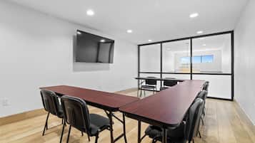 A conference room with a long wooden table, black chairs, and a large window with a view of the sky.