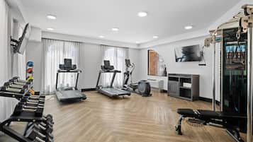 Un gimnasio moderno en casa con cintas de correr, una bicicleta estática y equipo de levantamiento de pesas.
