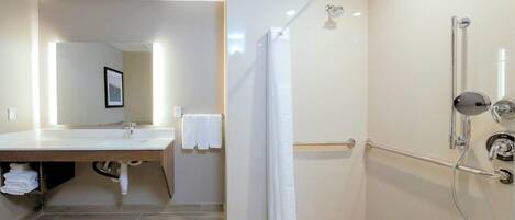 A modern bathroom with a shower, a sink, and a mirror.